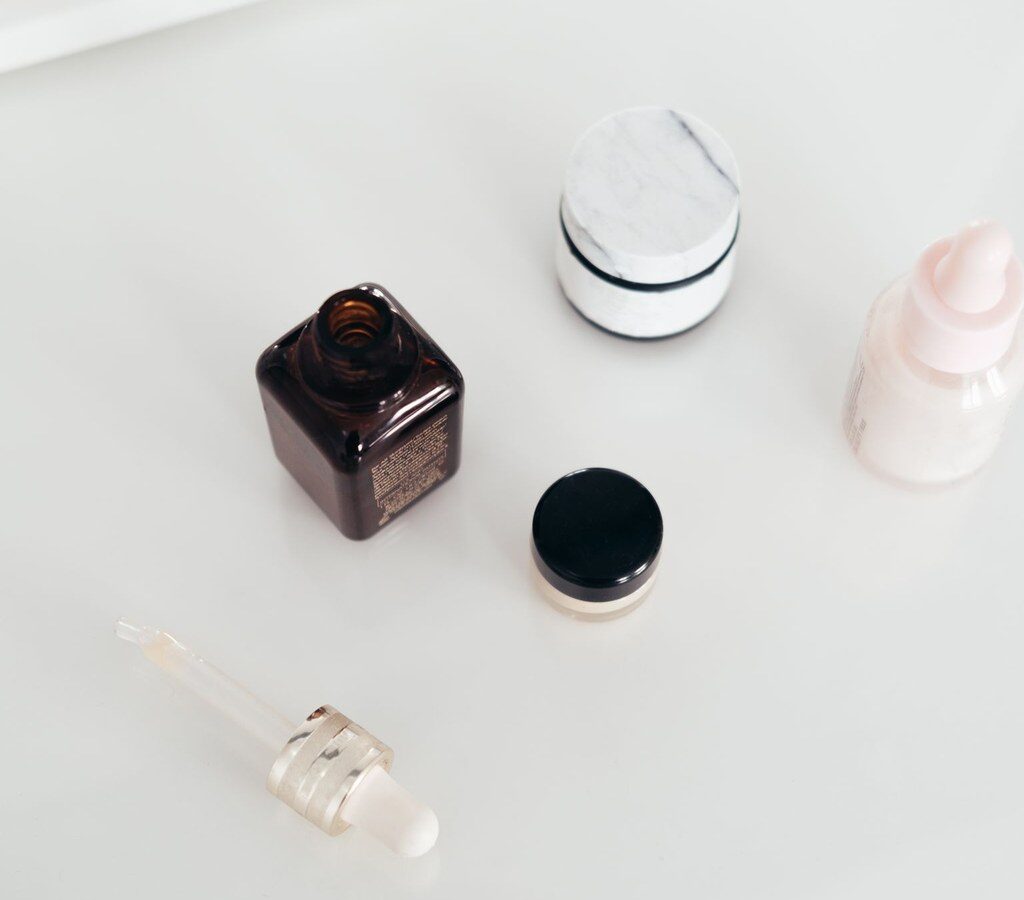 Fläschchen mit Pipette, Tiegel und Serumflasche auf weißer Fläche