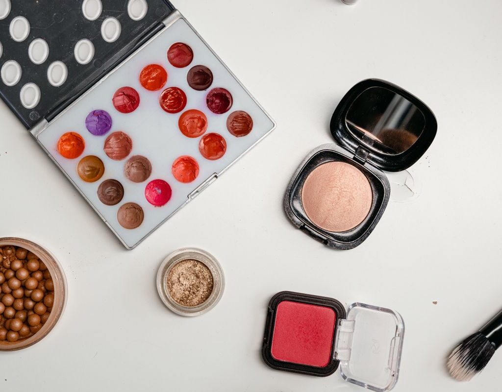 Verschiedene Make-up-Produkte und Pinsel von oben fotografiert