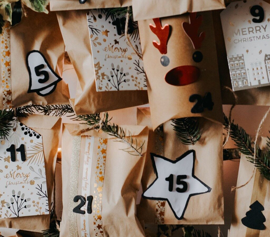 Selbst gebastelter Adventskalender aus braunen Papiertüten mit Zahlen, Tannenzweigen und Weihnachtsanhängern