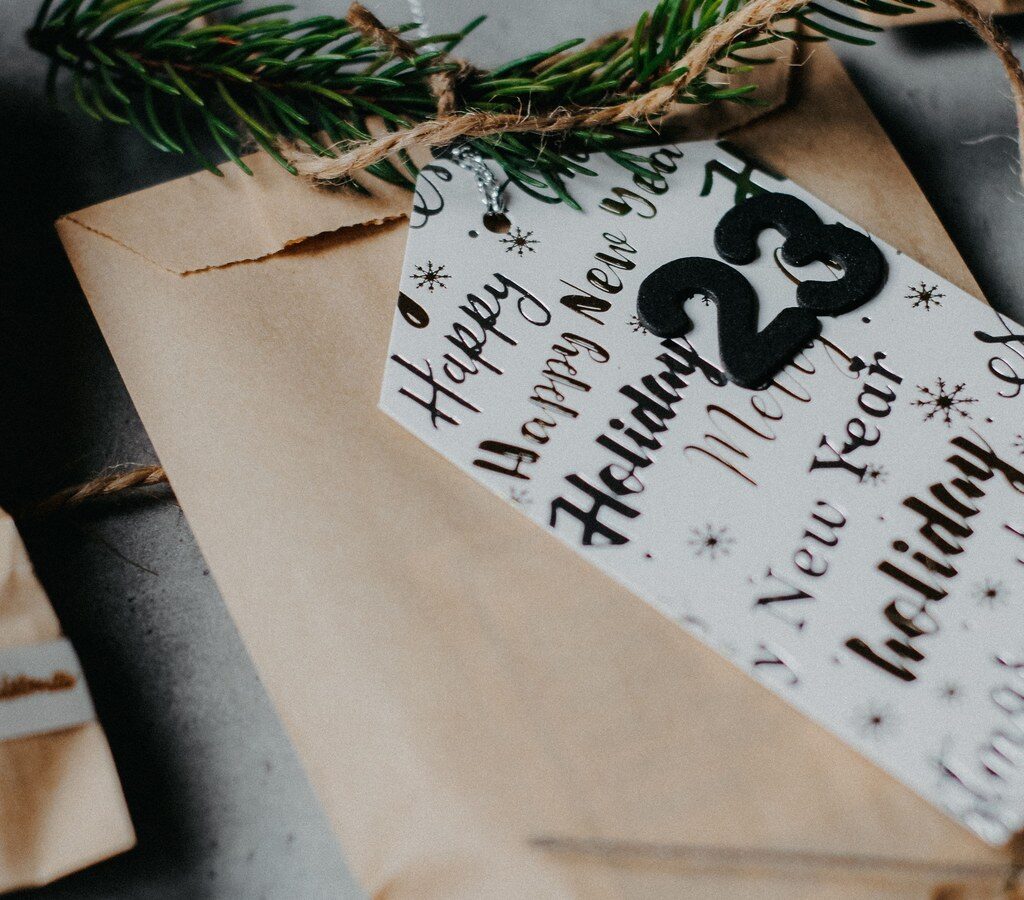 Kraftpapier-Säckchen mit Tannenzweig und weißem Zahlenanhänger, wie sie für selbst gepackte Adventskalender genutzt werden